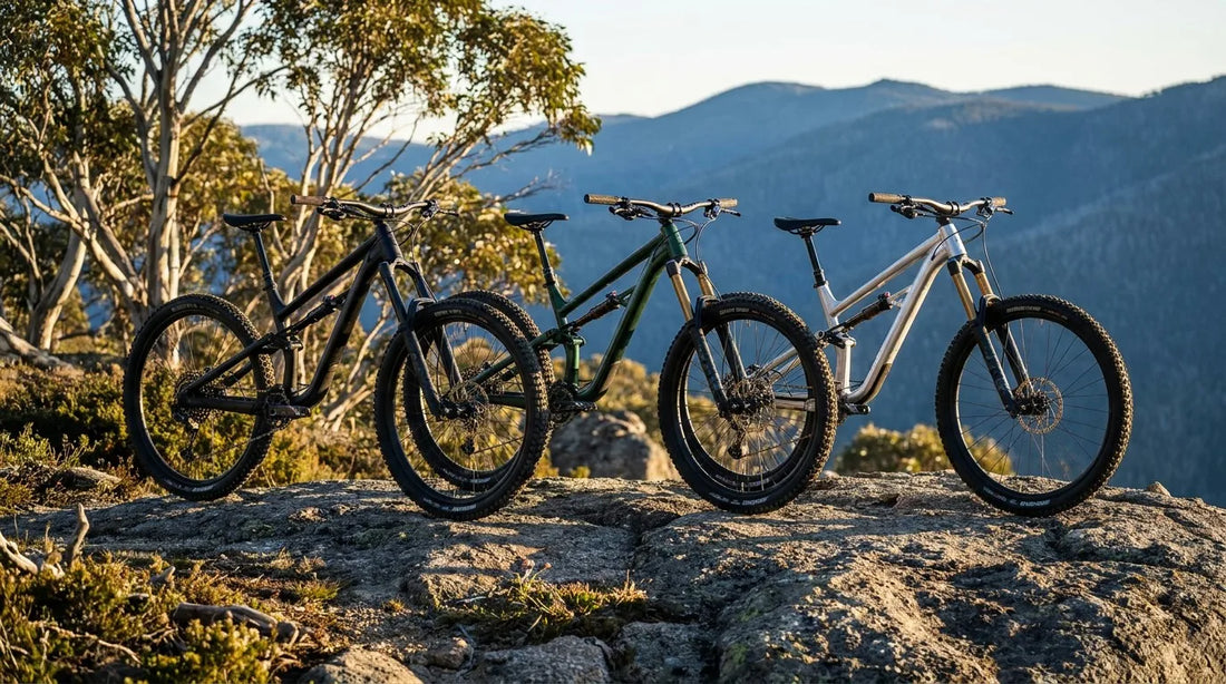 Three aggressive mid-tier mountain bikes lined up on a granite ledge in the Australian high country at golden hour.