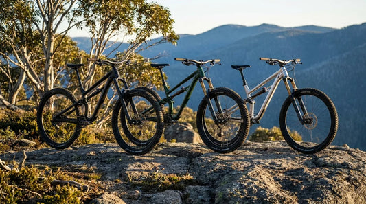 Three aggressive mid-tier mountain bikes lined up on a granite ledge in the Australian high country at golden hour.