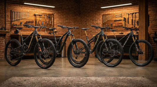 Four high-end carbon mountain bikes with Fox Factory suspension lined up in a professional workshop.