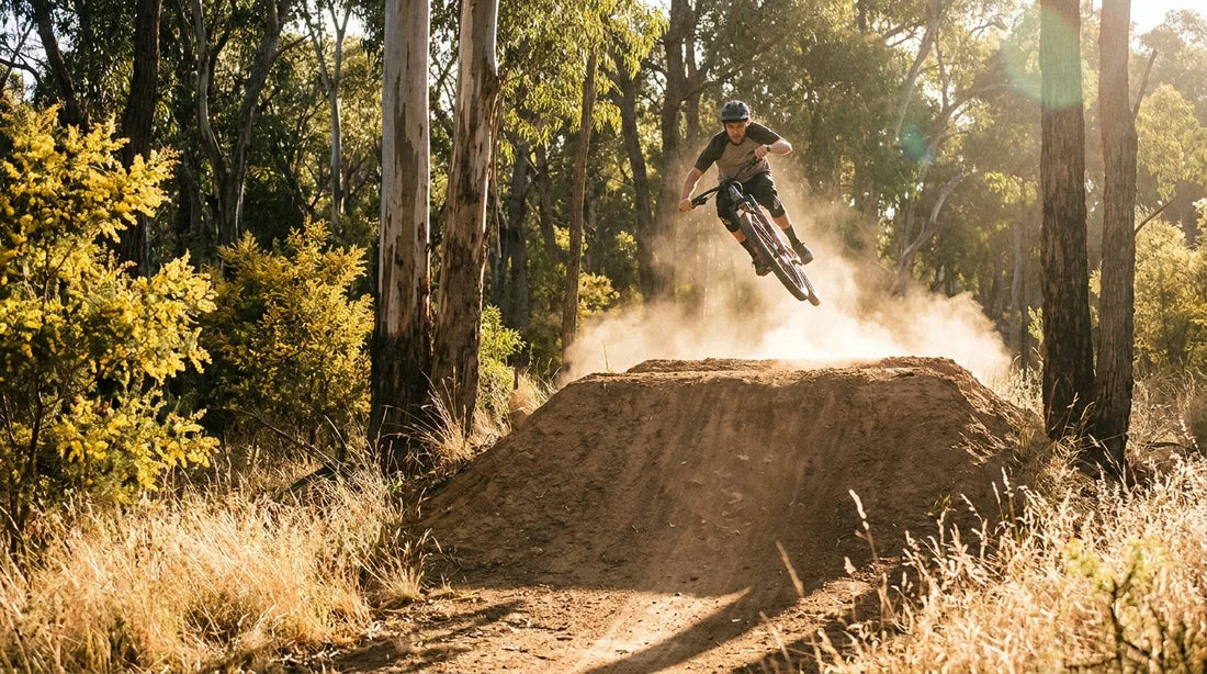 A mountain biker hitting a large dirt jump in an Australian bush setting at golden hour.