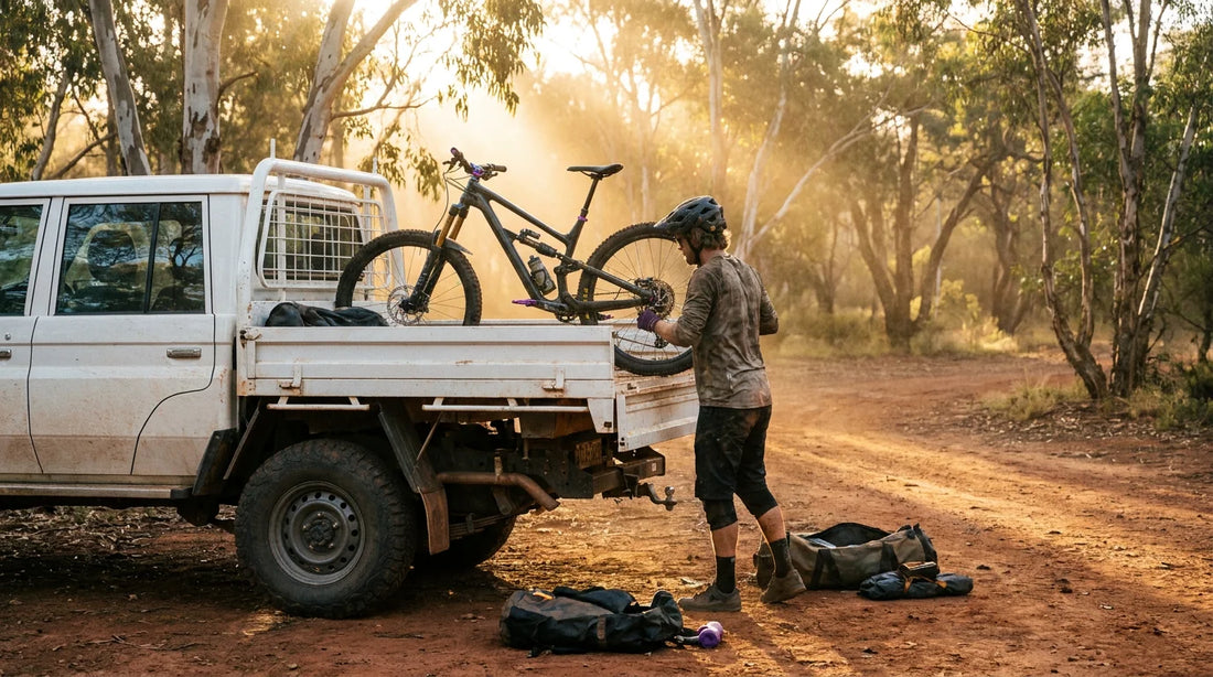 Mountain biker loading MTB into LandCruiser ute at Australian trailhead at golden hour
